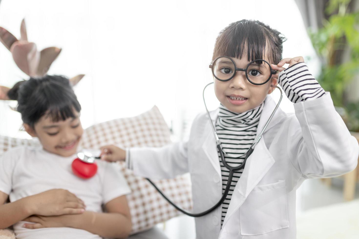 Two cute children play doctor and hospital using stethoscope. Friends girls having fun at home or preschool. photo