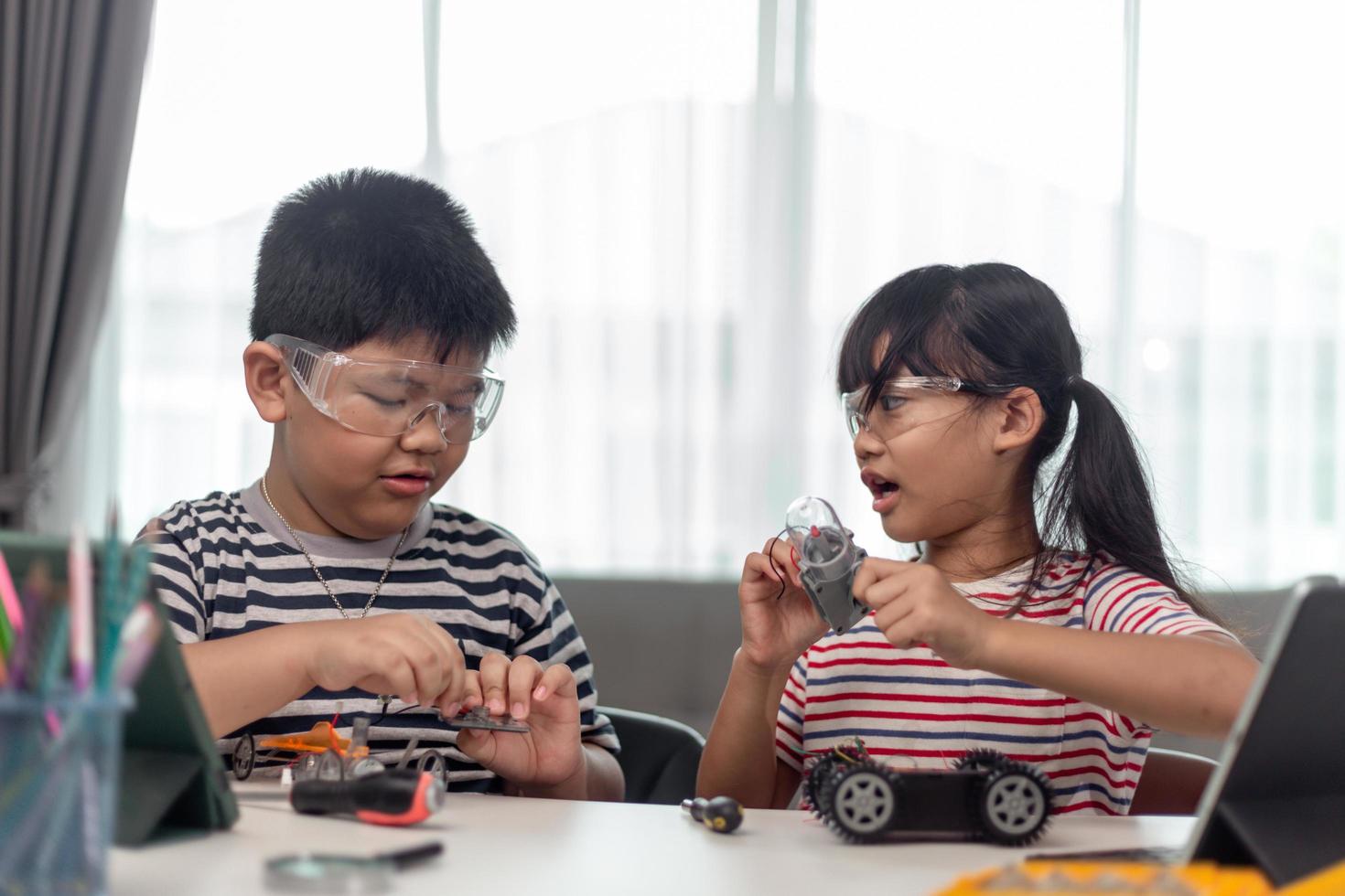 two Asian children having fun learning coding together, learning remotely at home, STEM science, homeschooling education, fun social distancing, isolation, new normal concept photo