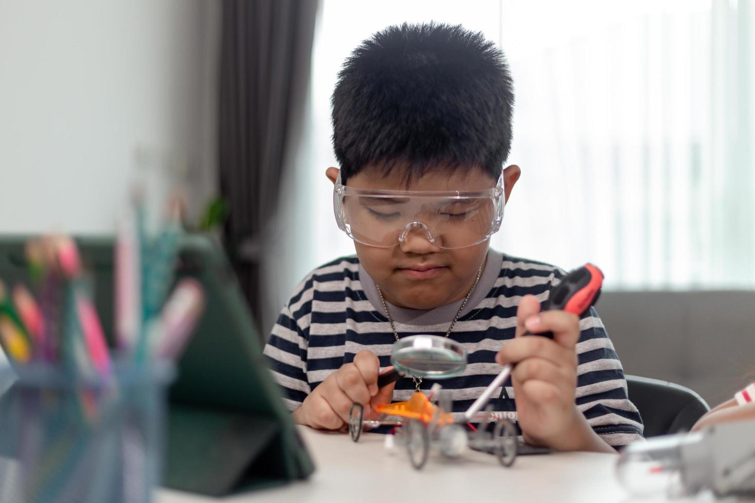 Young asia student remotely learn online at home  in coding robot car and electronic board cable in STEM, STEAM, mathematics engineer science technology computer code in robotics for kids. photo