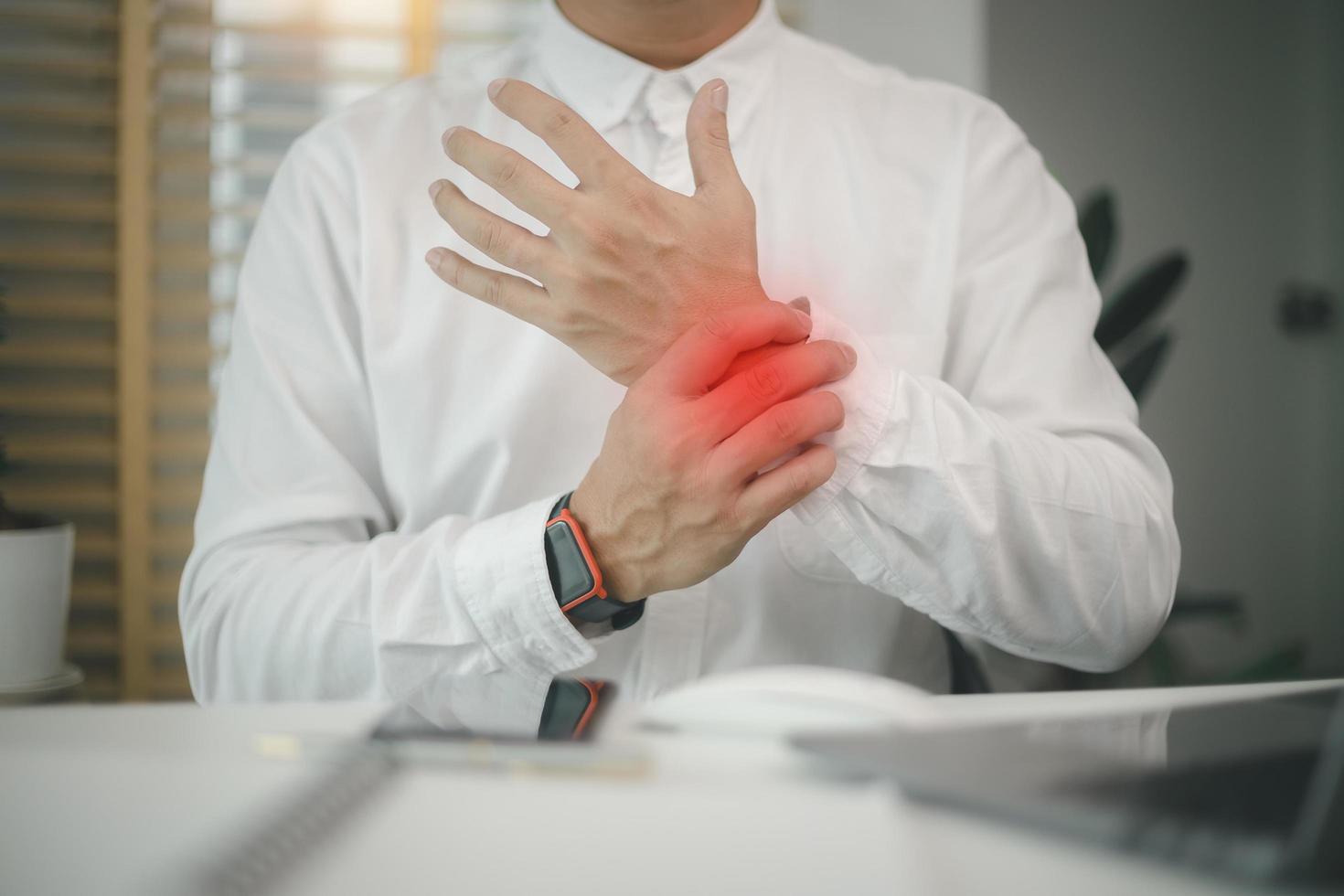 Male employee sitting office workplace with laptop, massaging sore wrist, suffering pinched nerve, stiff muscles, carpal tunnel syndrome after typing on laptop photo