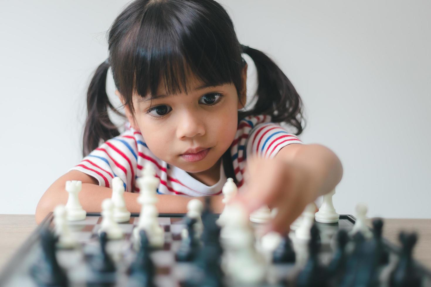 Asian little girl playing chess at home.a game of chess photo