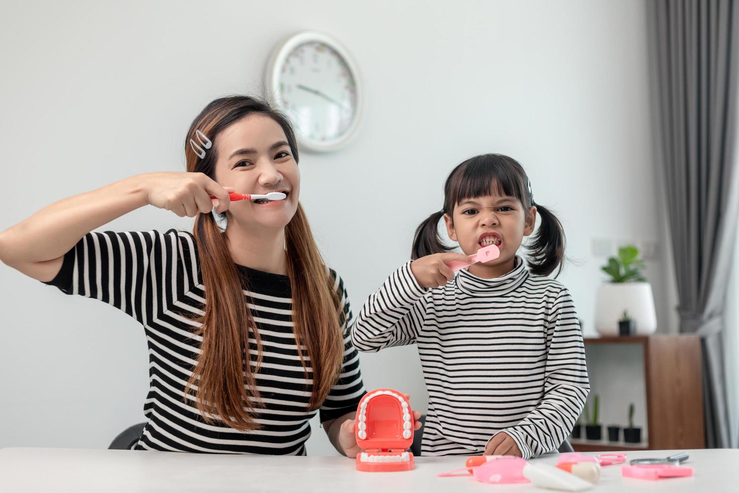 familia feliz y salud. madre e hija niña cepillándose los dientes juntos foto