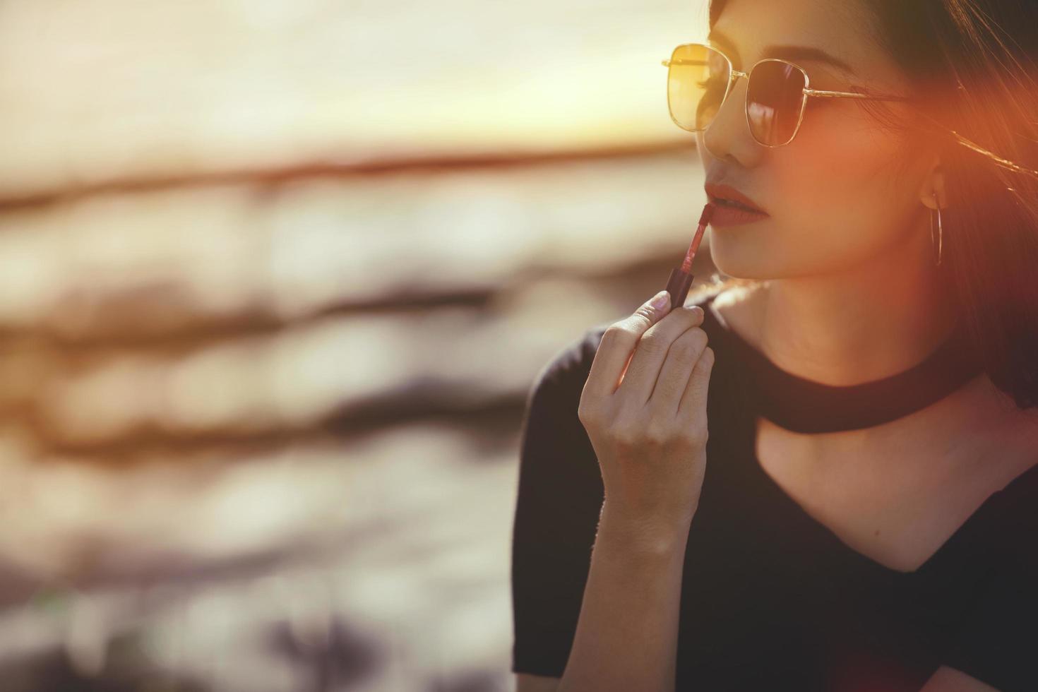 mujer sexy haciendo mujer maquillada aplicando pintalabios al aire libre.color retro foto