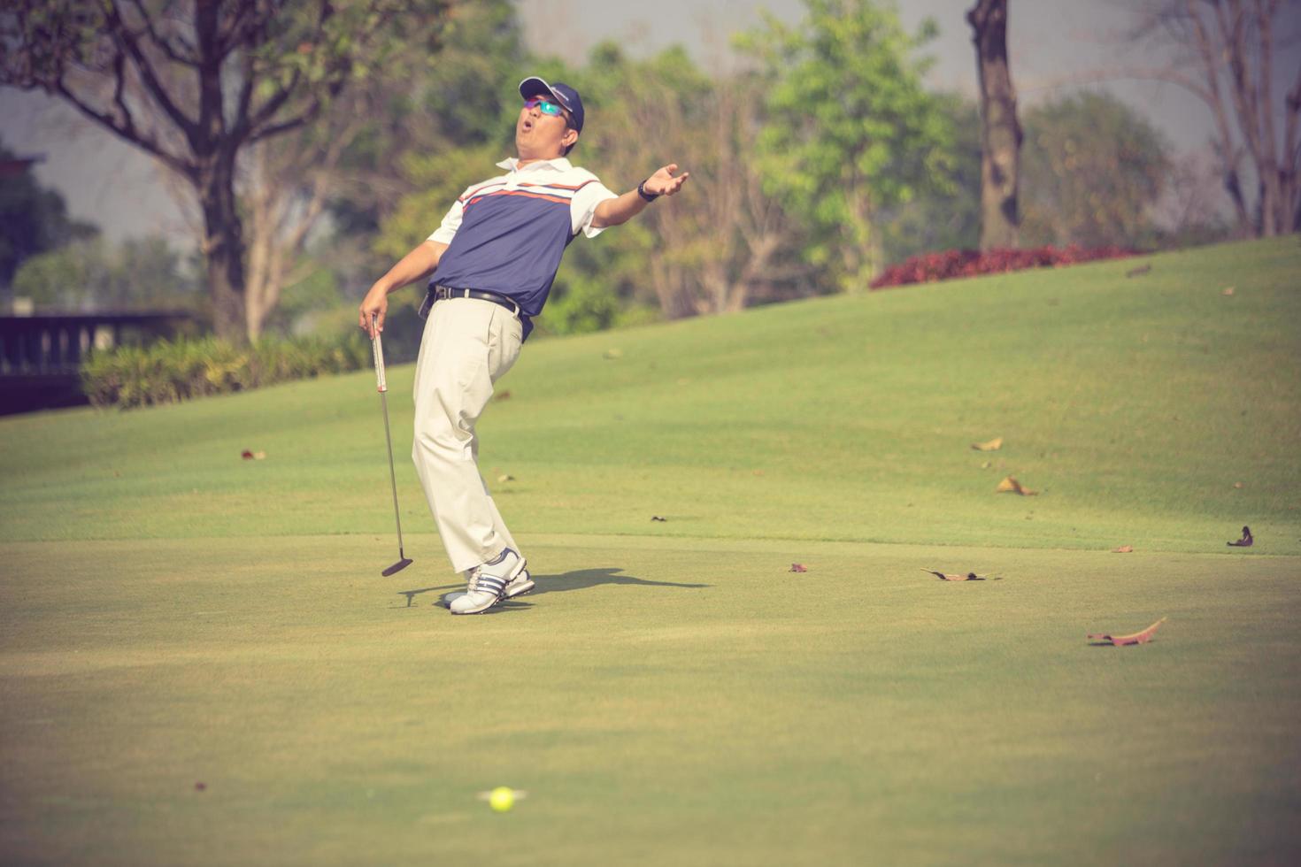 Golf player at the putting green hitting ball into a hole.Vintage color photo