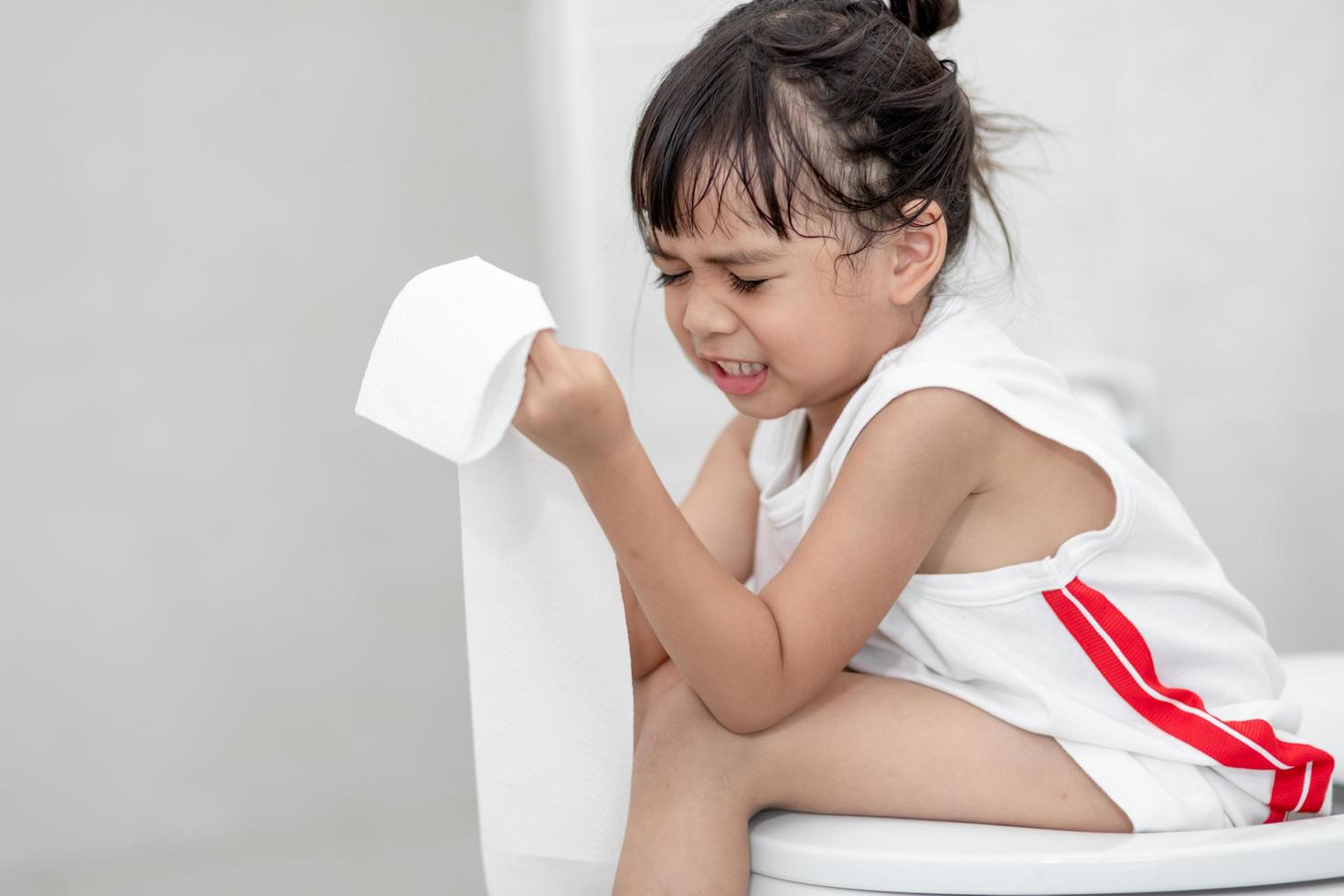 The little girl is sitting on the toilet suffering from constipation or hemorrhoid. photo