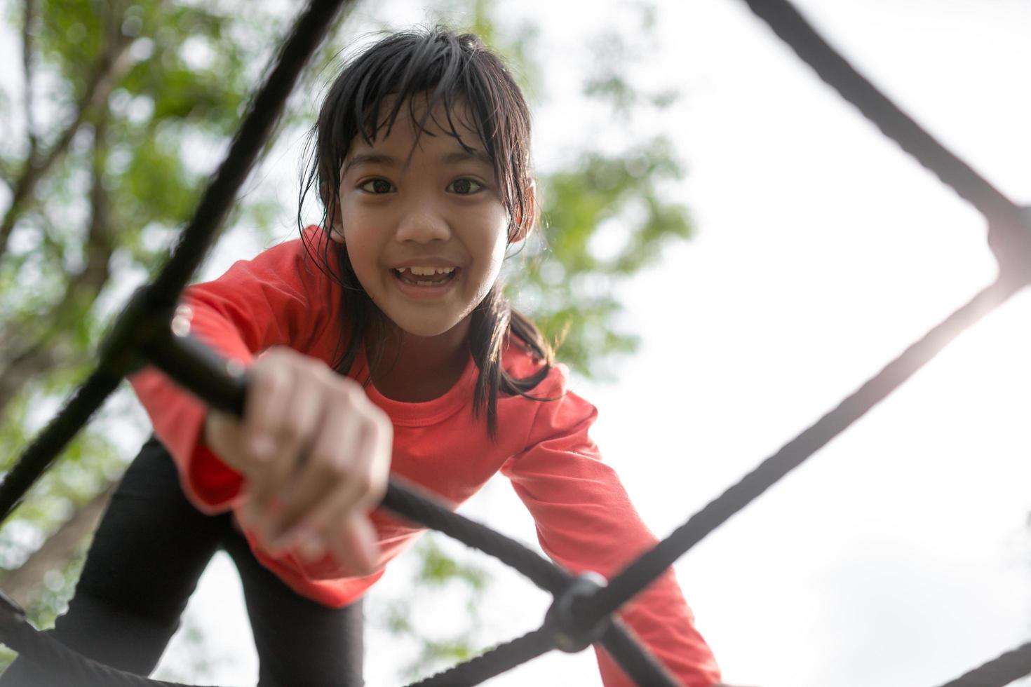 niña asiática disfruta jugando en un parque infantil, retrato al aire libre foto