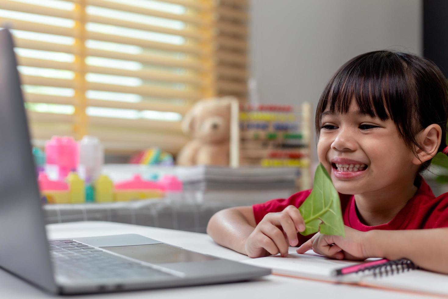 Learning time. Interested little kid schoolgirl in headset sit at home desk watch education video lesson. Curious small school age girl think on teacher question select correct answer on laptop screen photo