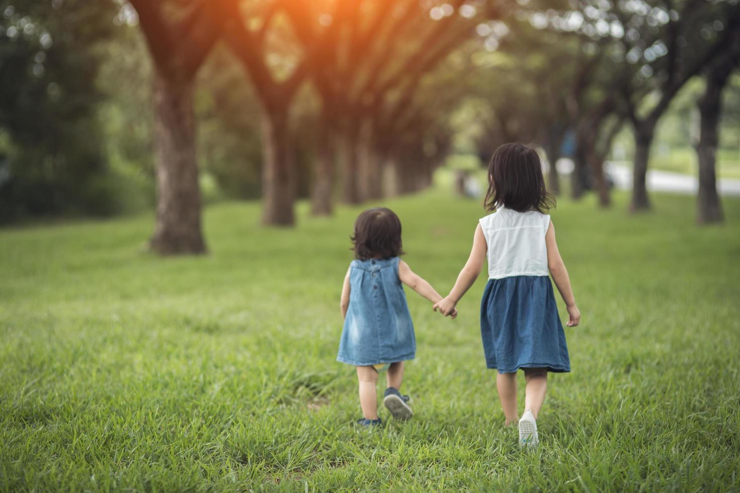 Two little sisters holding each other hands and running forward.Vintage color photo