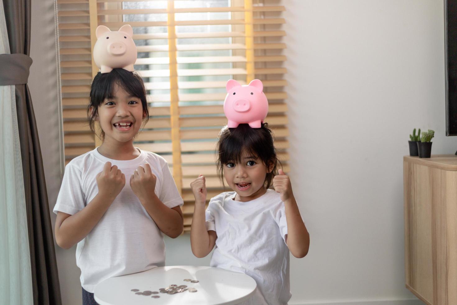 Little Asian girl saving money in a piggy bank, learning about saving, Kid save money for future education. Money, finances, insurance, and people concept photo