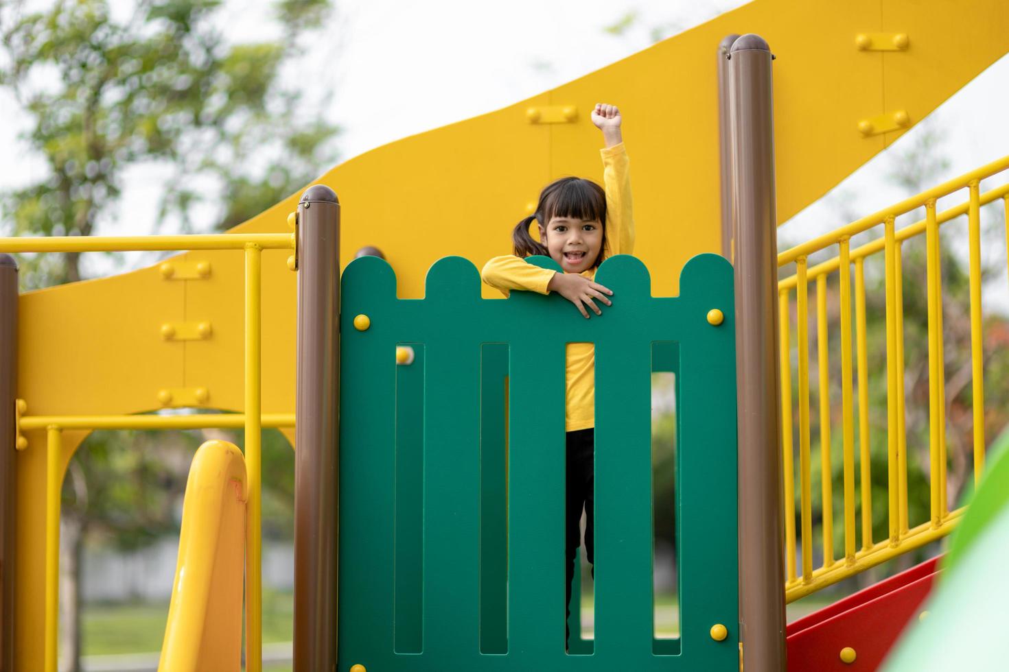 Child playing on outdoor playground. Kids play on school or kindergarten yard. Active kid on colorful slide and swing. Healthy summer activity for children. Little girl climbing outdoors. photo