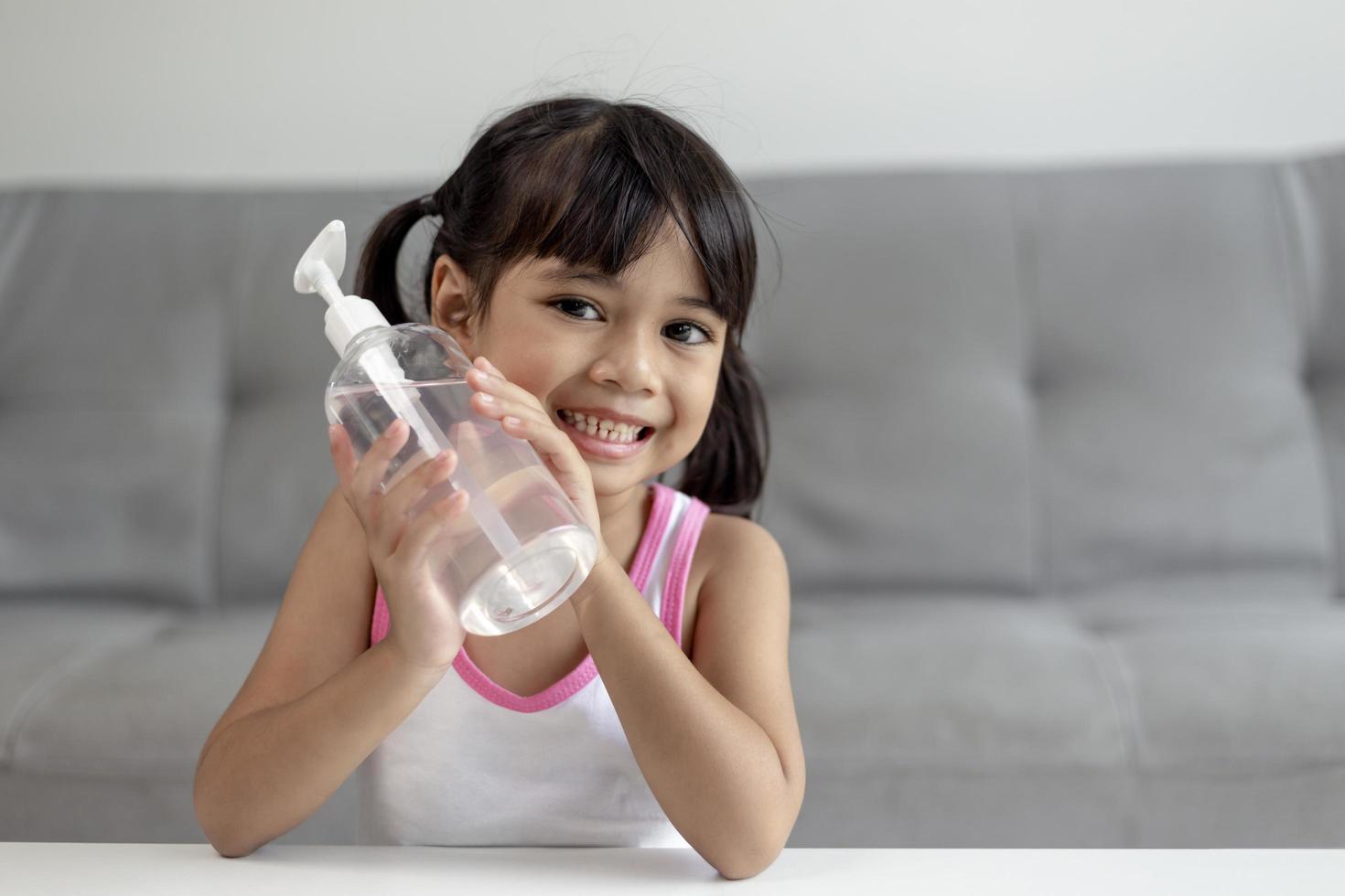 Little Asian girl child put alcohol gel sanitizer pump on Hands for cleaning or wash his hands. photo