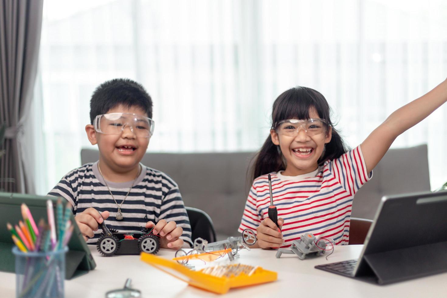 two Asian children having fun learning coding together, learning remotely at home, STEM science, homeschooling education, fun social distancing, isolation, new normal concept photo