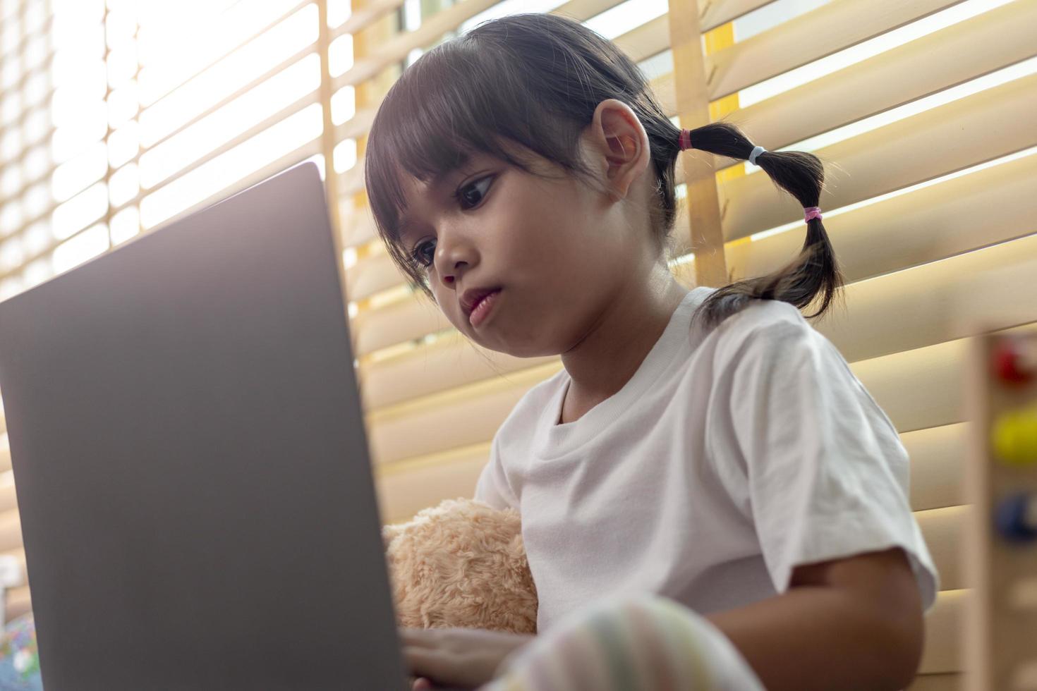 Asian girl using Laptop computer for online study homeschooling during home quarantine. homeschooling, online study, home quarantine, online learning, corona virus or education technology concept photo