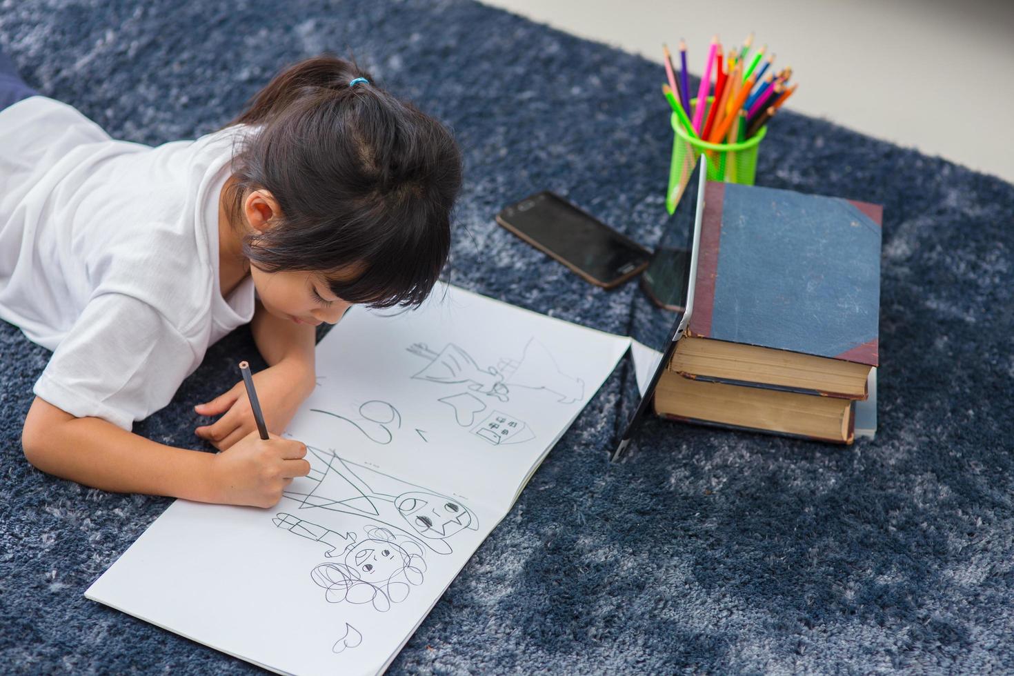 retrato de un niño en edad preescolar que usa una tableta para su tarea, enfoque suave de un niño que hace la tarea usando una tableta digital buscando información en Internet, aprendizaje electrónico o concepto de educación escolar en el hogar foto