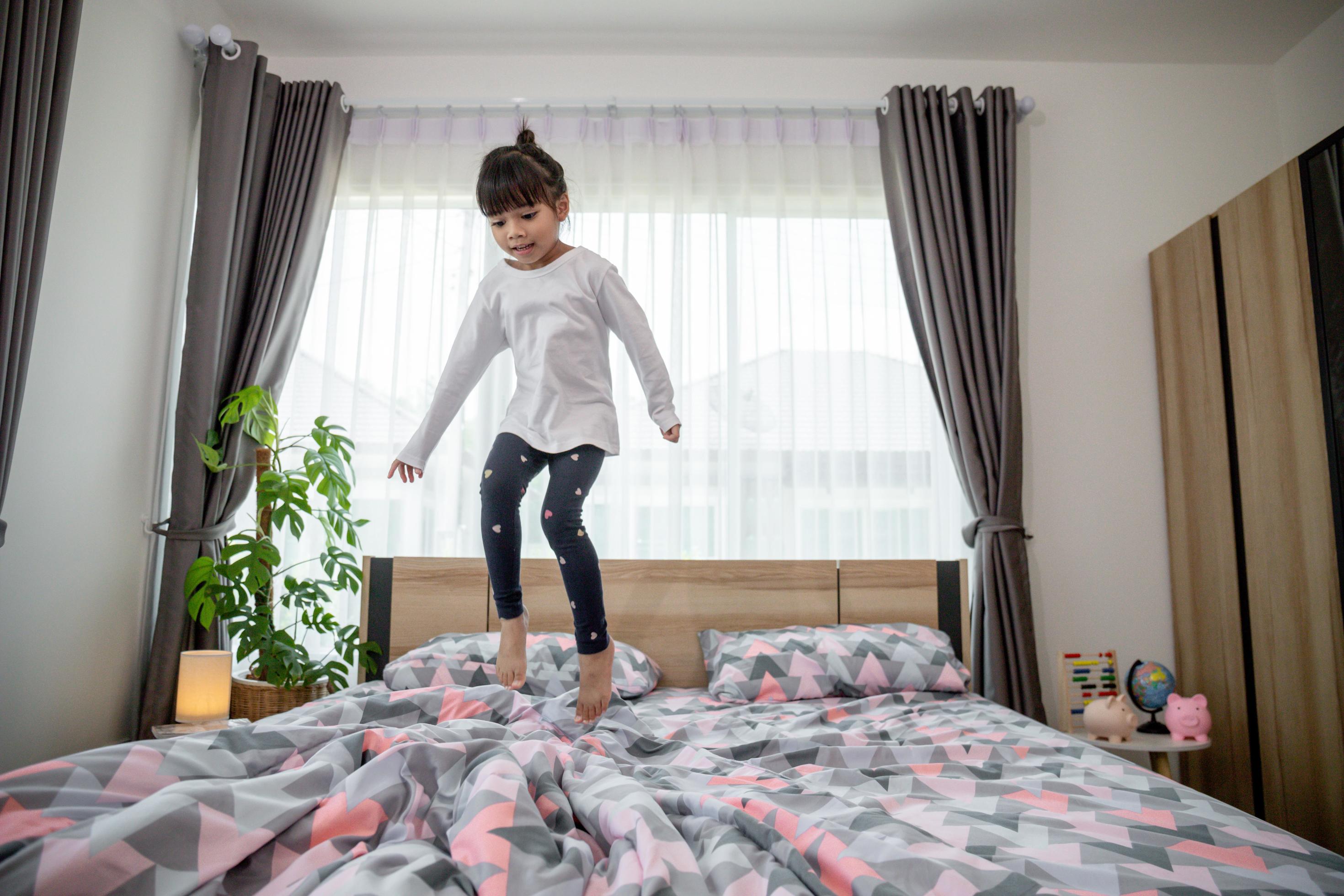 Cute little girl jumping on the bed 8428775 Stock Photo at Vecteezy