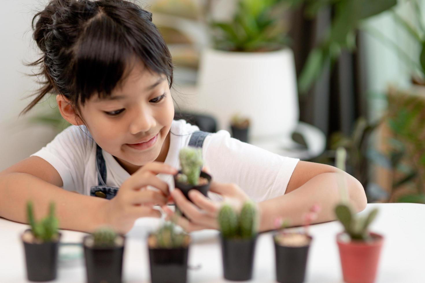 kid gently touch new stem of the cactus he grows with care, one hand holds magnifying glass.Nature education, Montessori and observation skills concept. photo