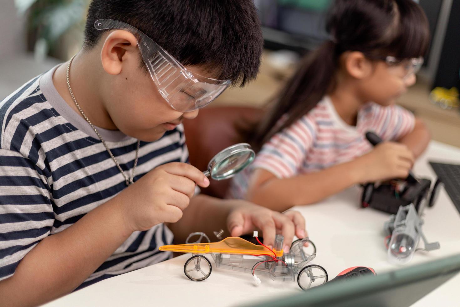 two Asian children having fun learning coding together, learning remotely at home, STEM science, homeschooling education, fun social distancing, isolation, new normal concept photo