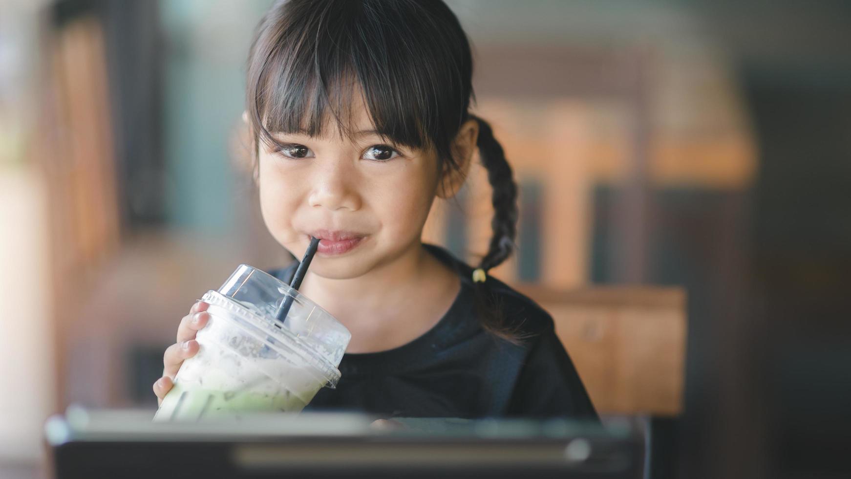 Cute asian children drinking fresh juice in the cafe photo