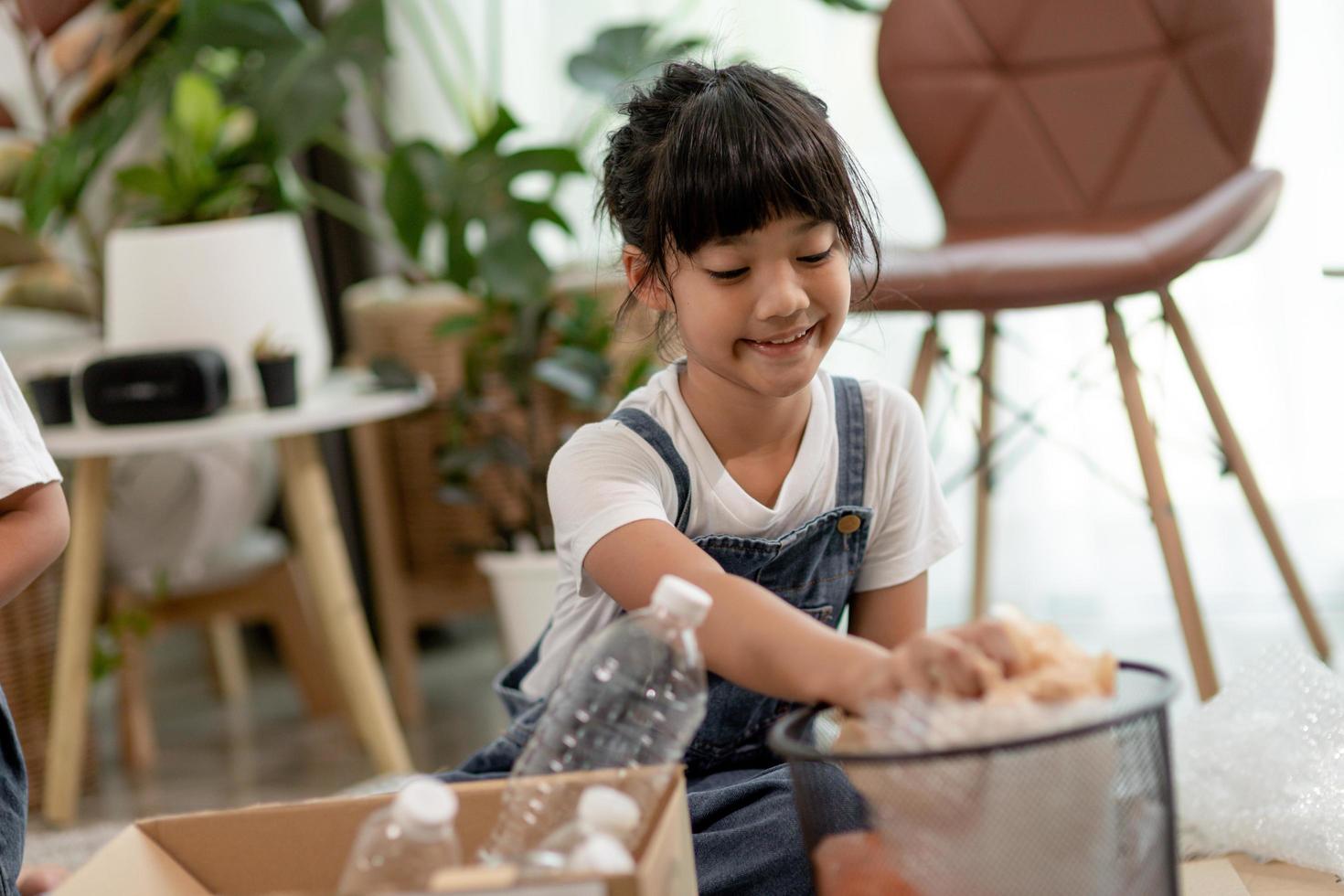 Smiling children having fun while segregating plastic bottles and paper into a bin photo