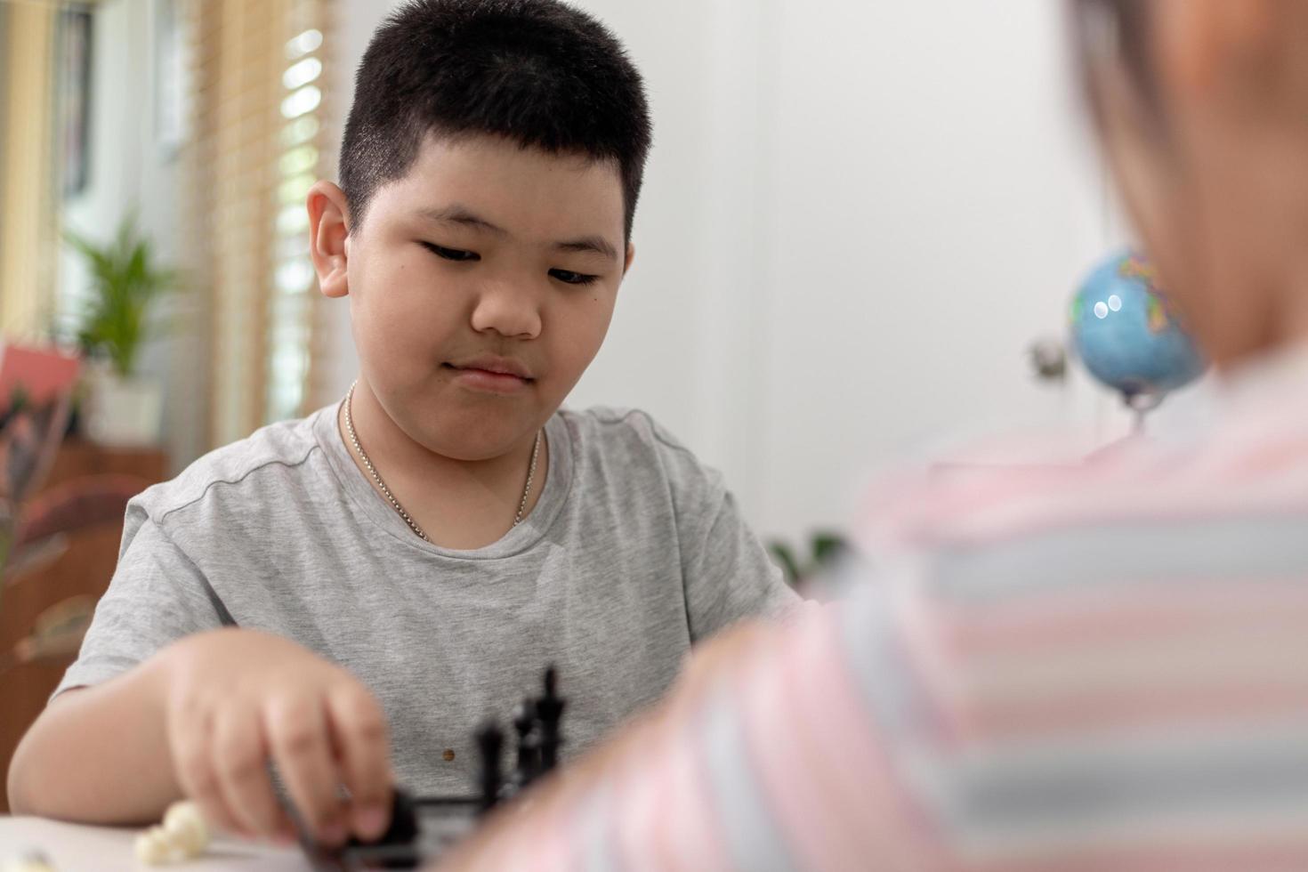 Little boy and little girl are playing chess at home.Children playing chess photo