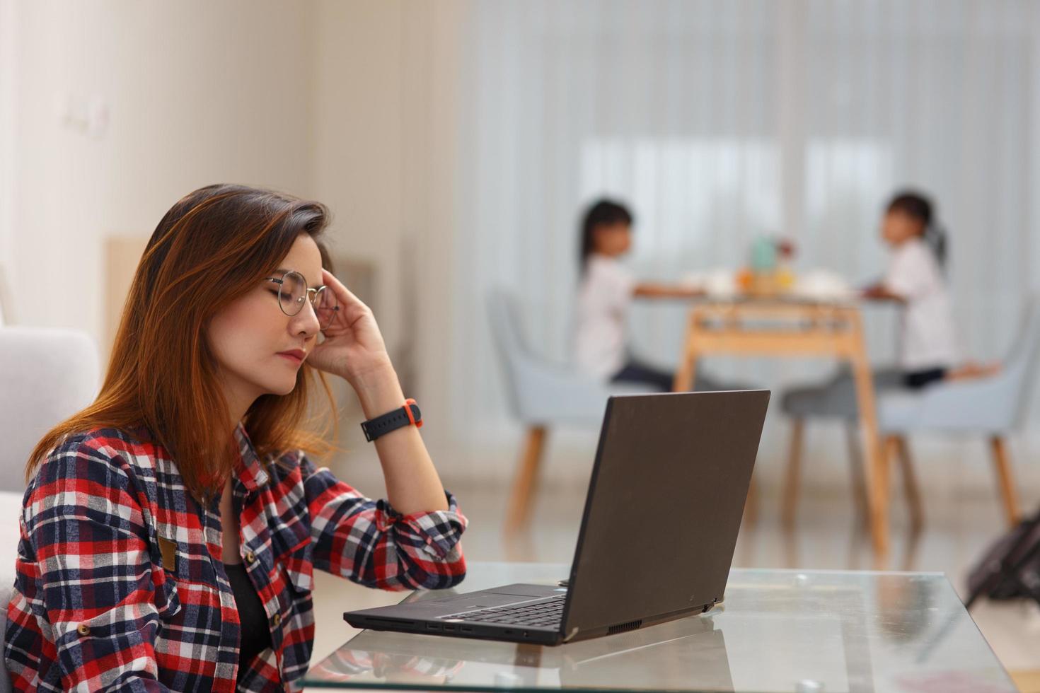 Mother working from home with kids. Quarantine and closed school during coronavirus outbreak. Children make noise and disturb woman at work. Homeschooling and freelance job. photo