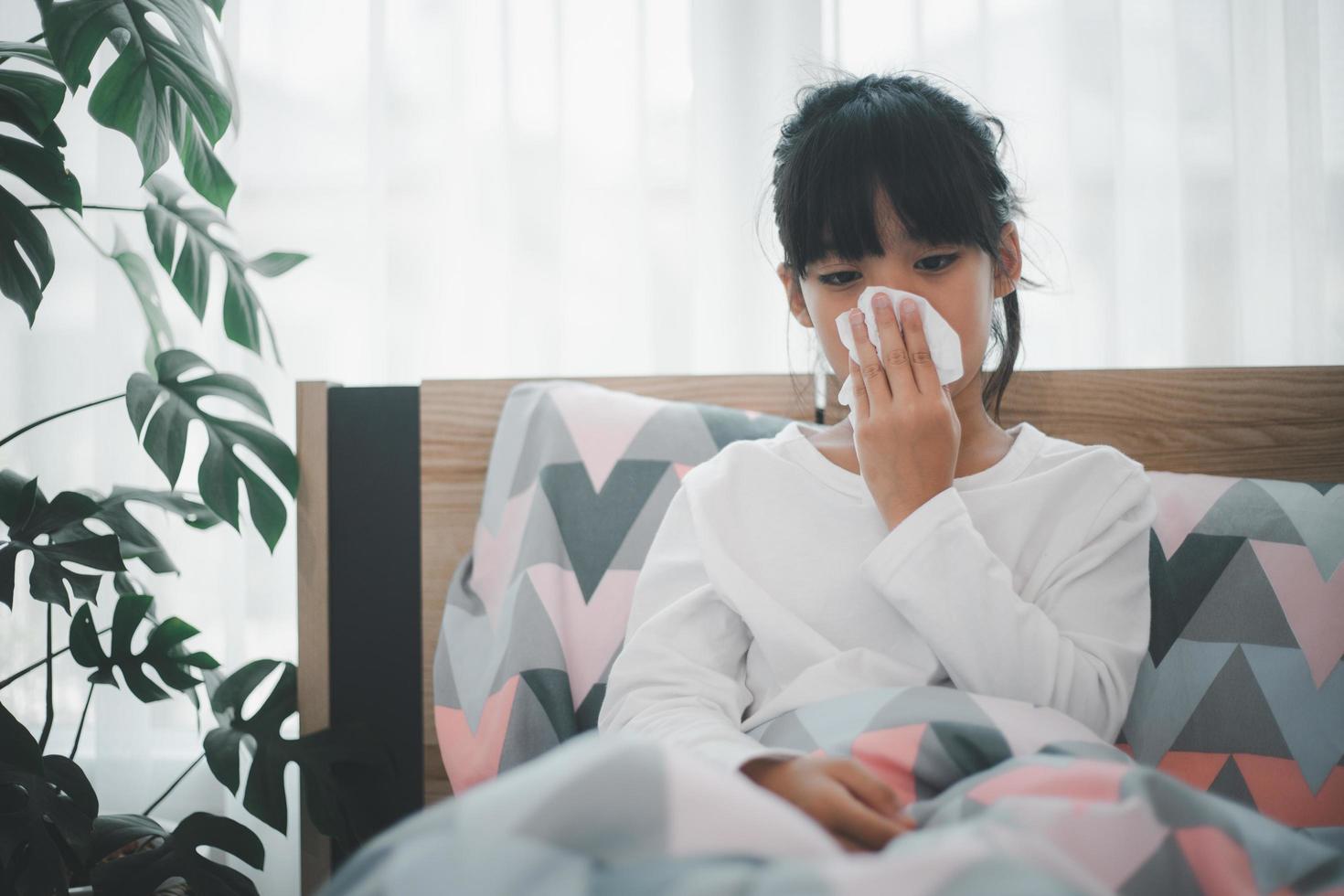 little girl gets cold and blows her nose at home. photo