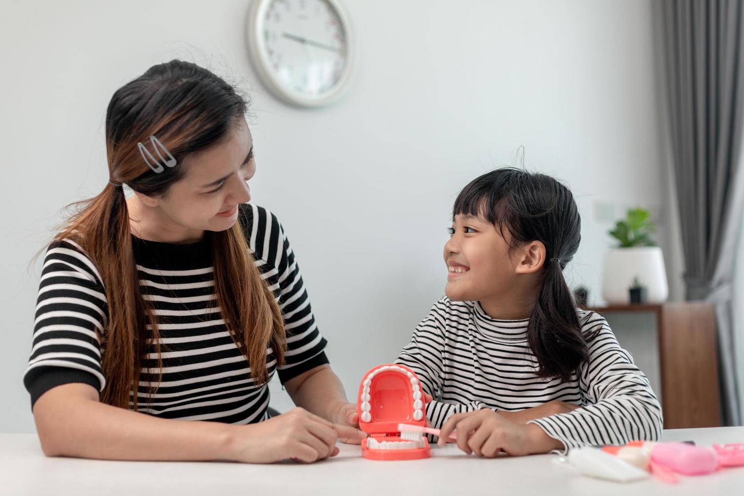 mother teaching daughter child teeth brushing at home photo