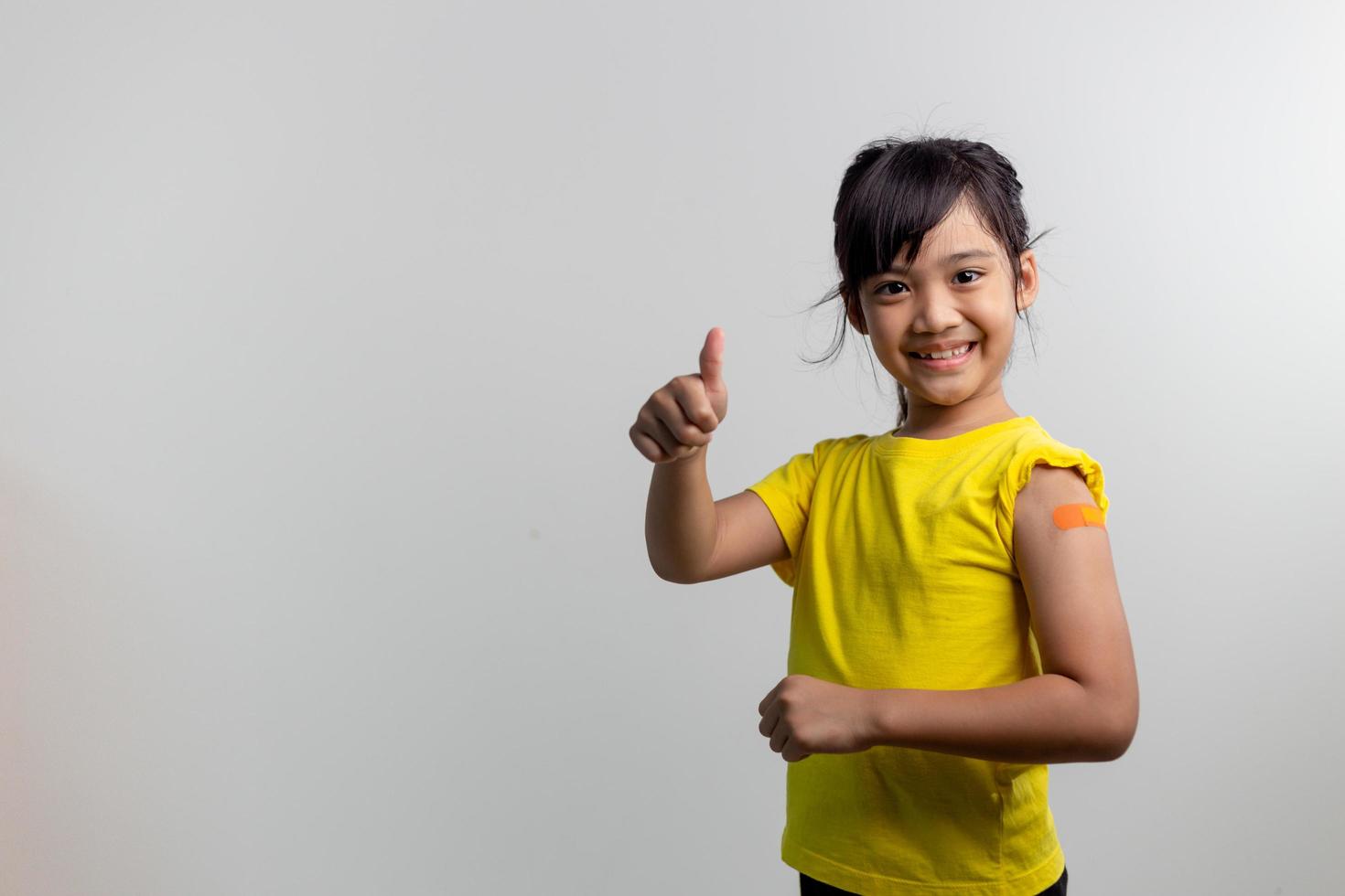 COVID 19 Vaccines for Kids concept. Studio a portrait of an adorable Asian girl after getting his first dose of vaccine. Immune, Safe, Available, Back to school. photo