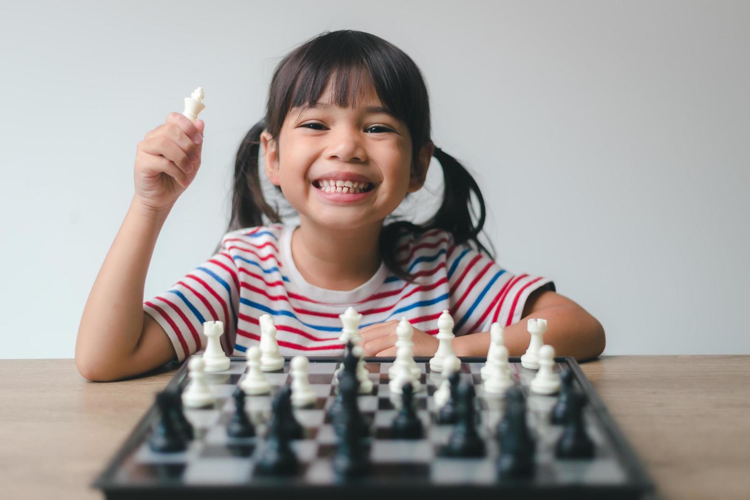 Asian little girl playing chess at home.a game of chess photo