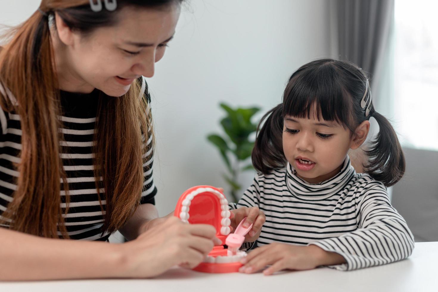 Mother teaches her child daughter accurately brushing teeth photo