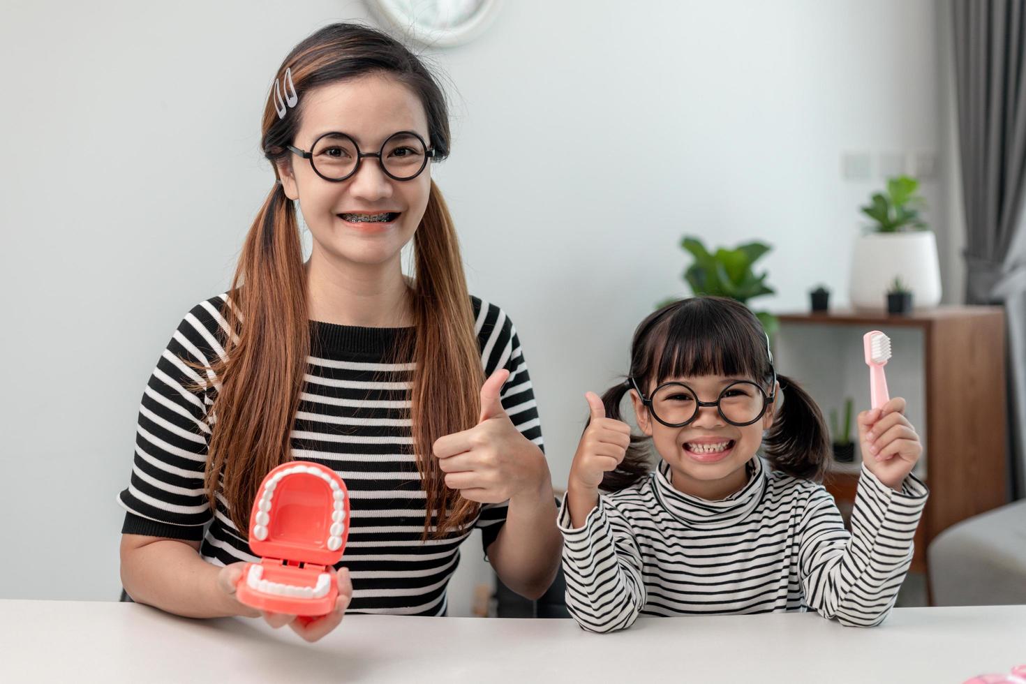 mother teaching daughter child teeth brushing at home photo