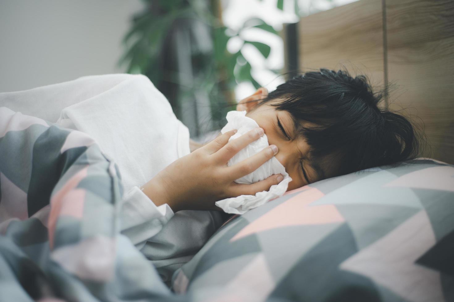 little girl gets cold and blows her nose at home. photo