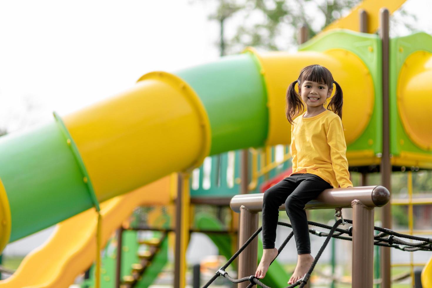 Asian child girl playing on the playground in the outdoor park.Happy moment and good emotion photo