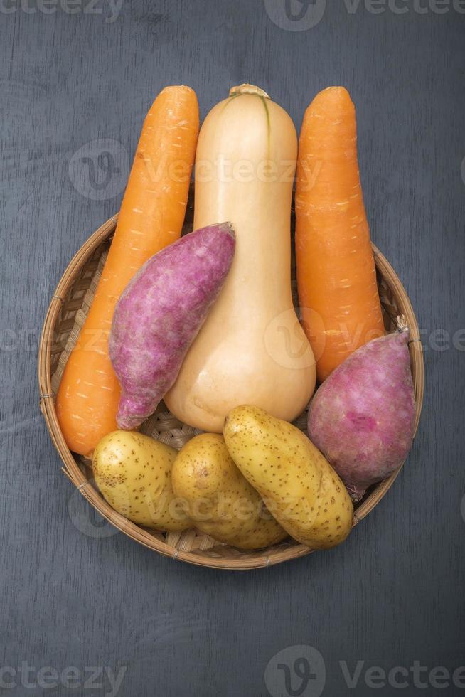 Healthy food butternut squash carrot sweet potato in basket isolated on black wood background photo