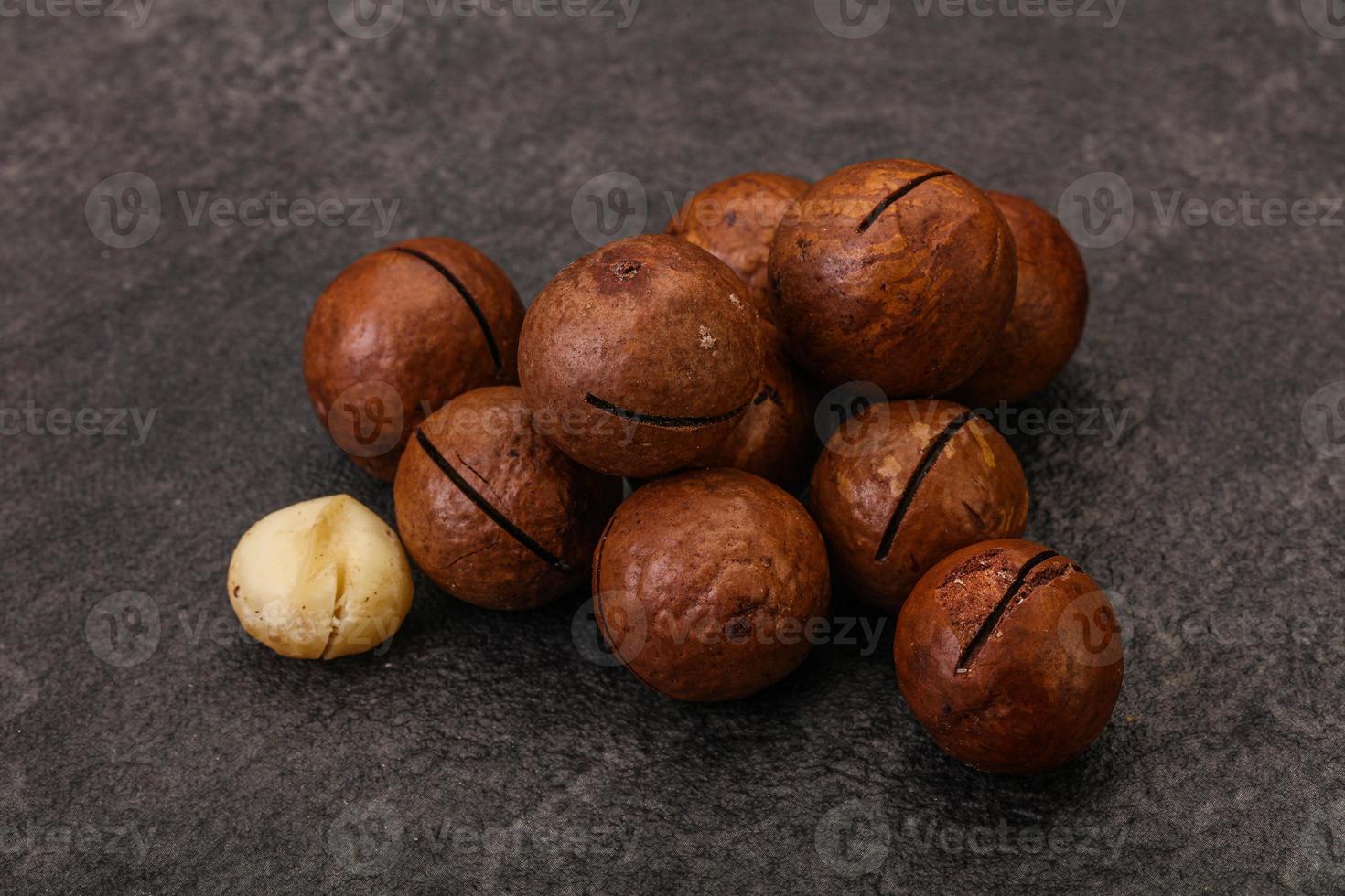 Brown macadamia nut heap over background photo
