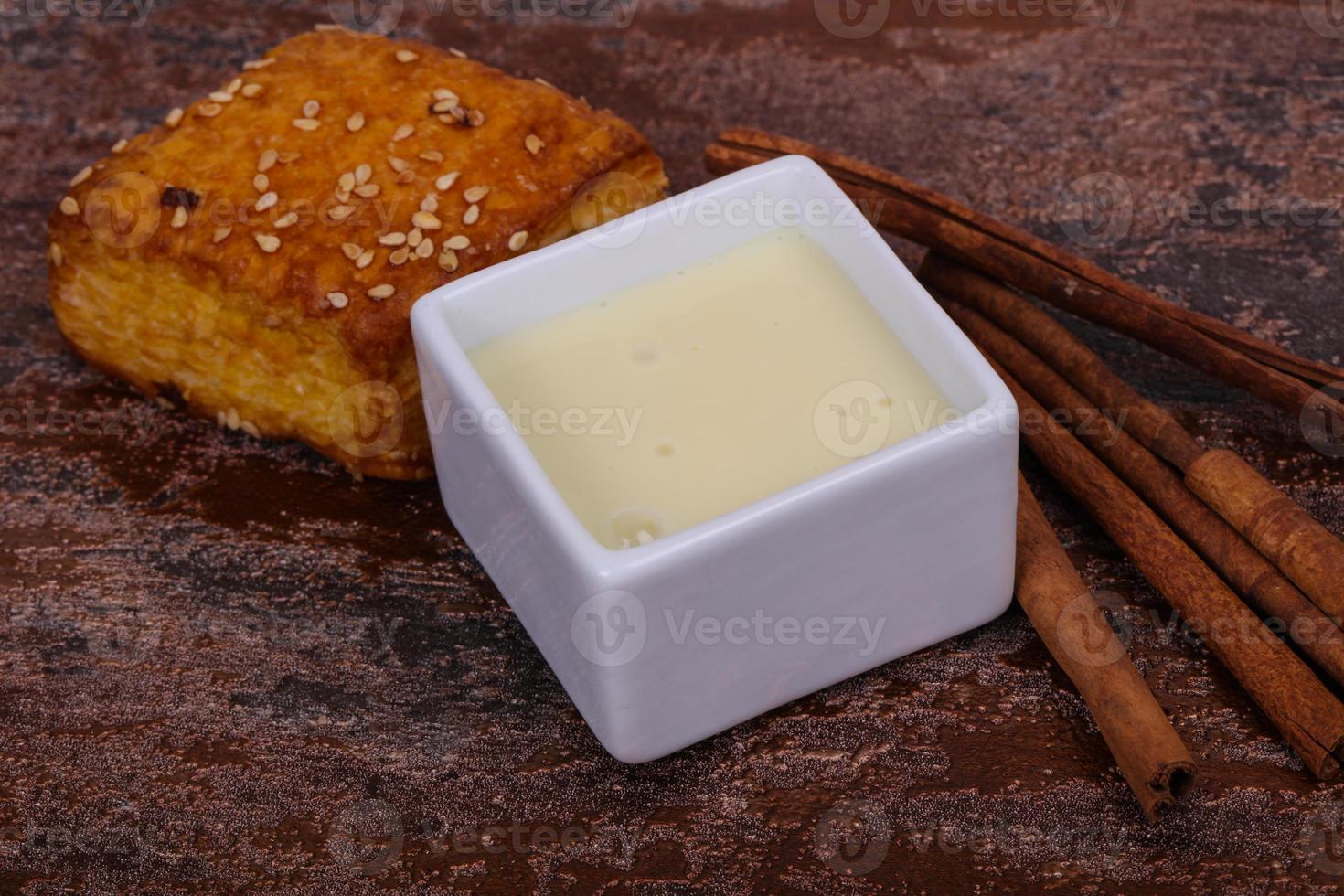 Condenced milk in the bowl with sinnamon and pastry photo