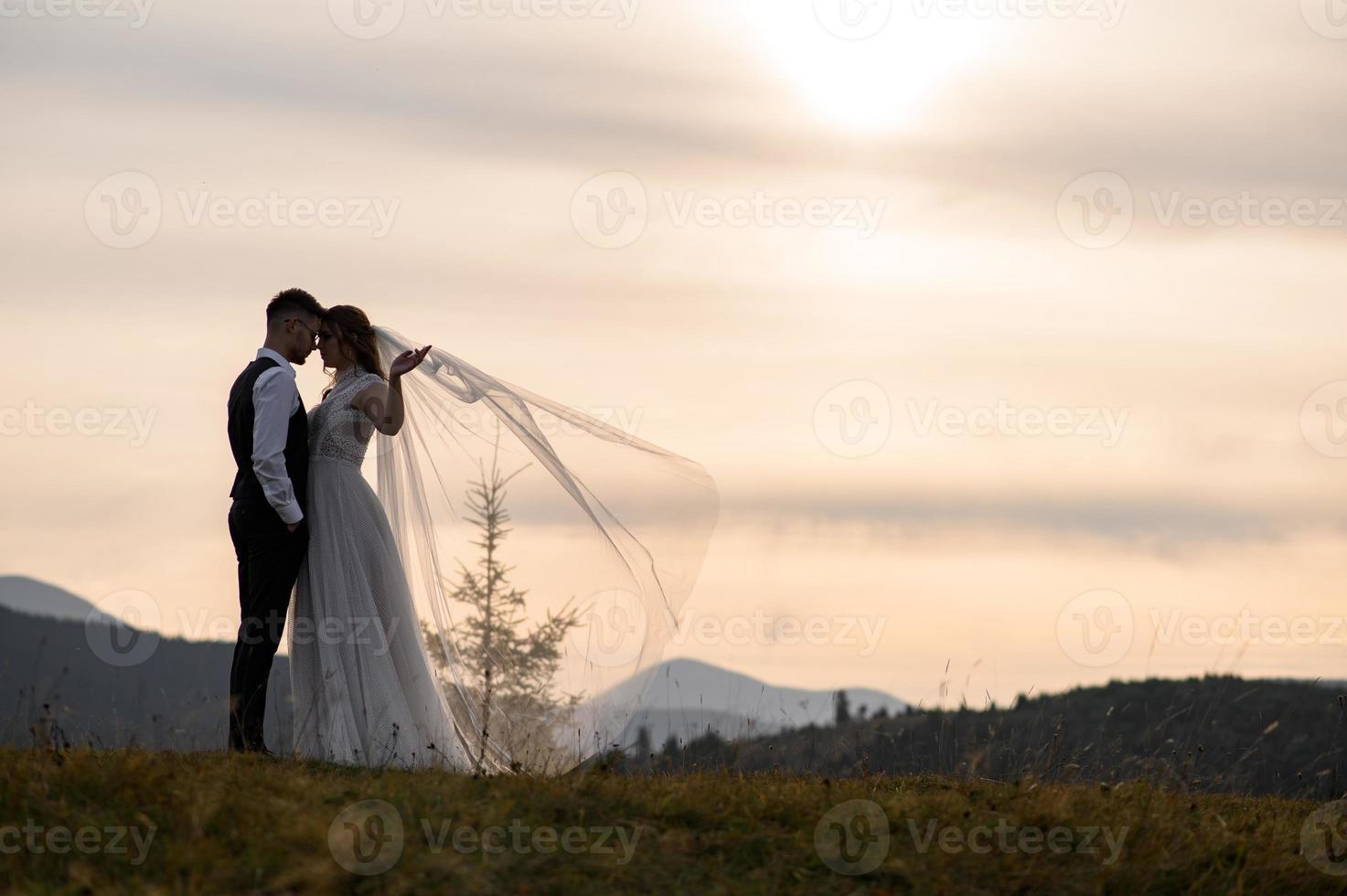 happy stylish bride and groom running and having fun in mountains on summer sunny day photo