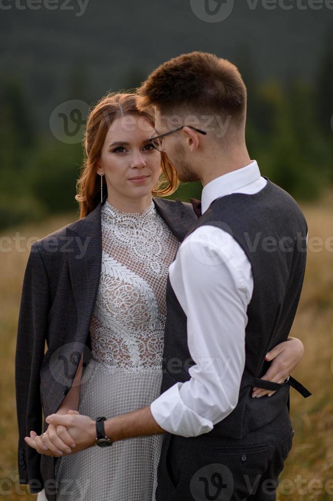 happy stylish bride and groom running and having fun in mountains on summer sunny day photo