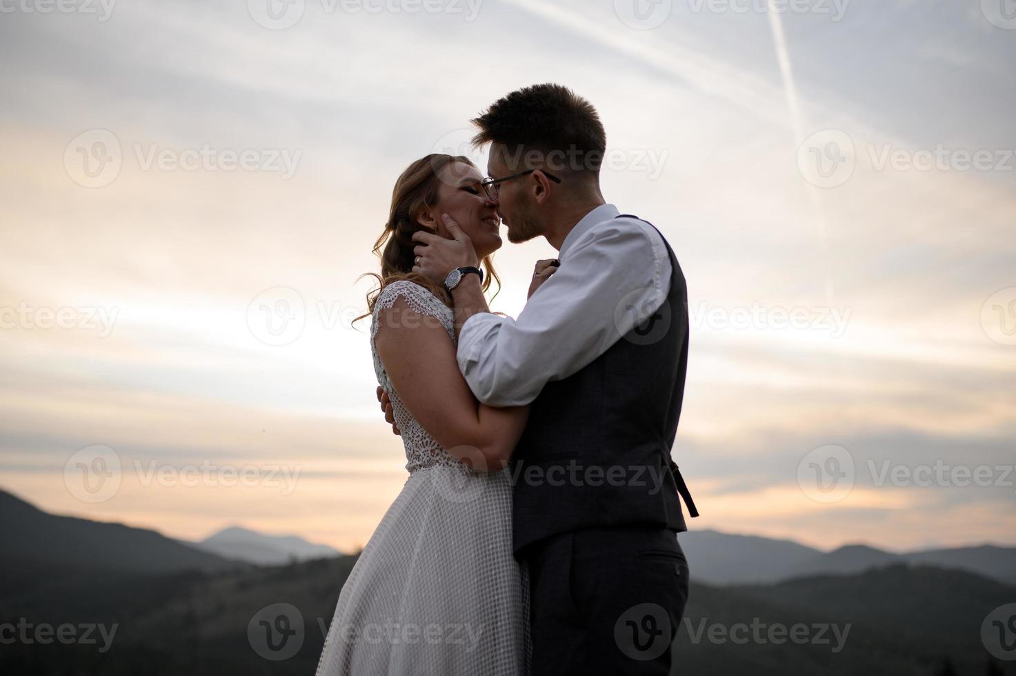 happy stylish bride and groom running and having fun in mountains on summer sunny day photo