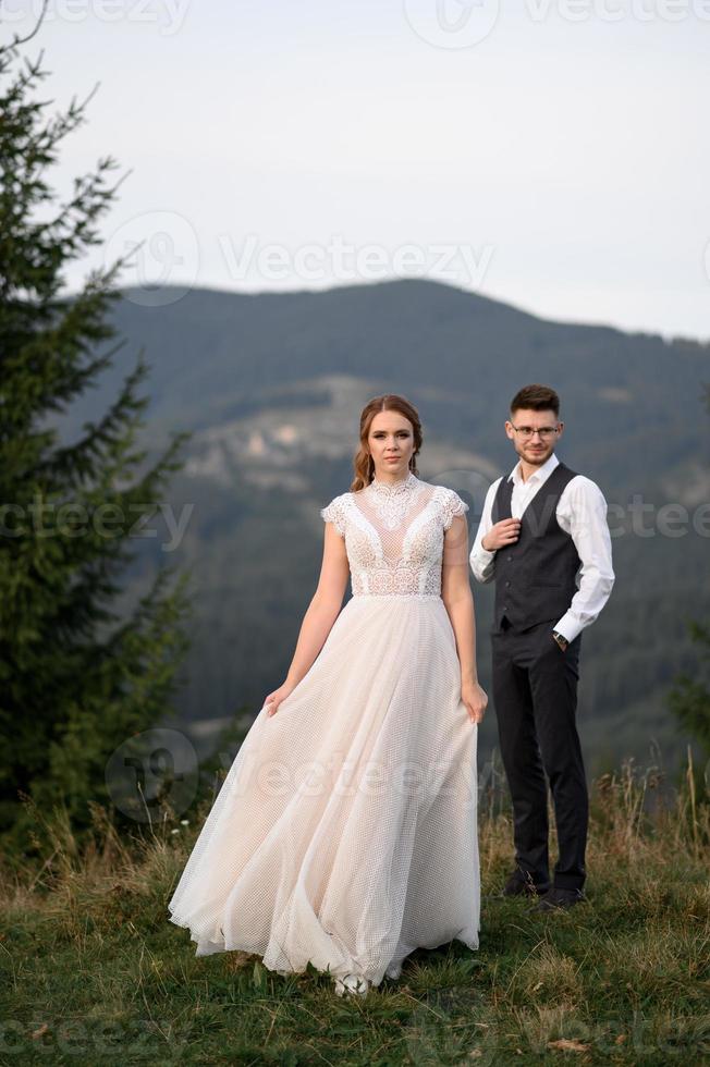 happy stylish bride and groom running and having fun in mountains on summer sunny day photo