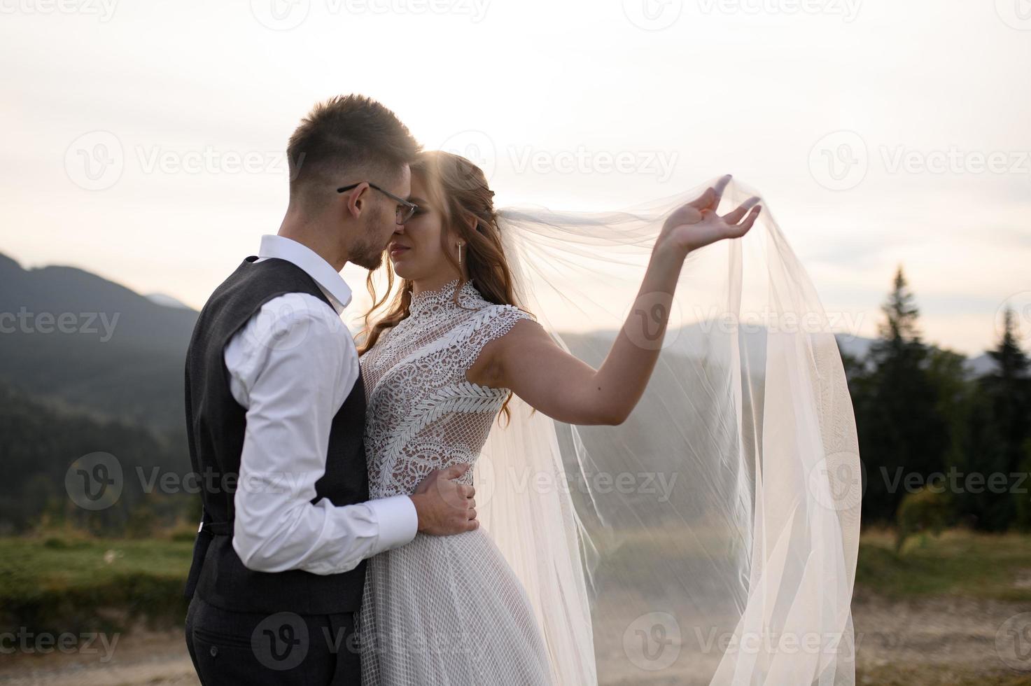 happy stylish bride and groom running and having fun in mountains on summer sunny day photo