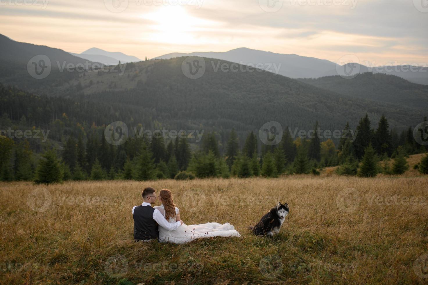 happy stylish bride and groom running and having fun in mountains on summer sunny day photo