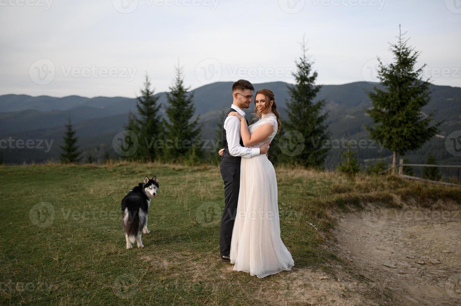 happy stylish bride and groom running and having fun in mountains on summer sunny day photo