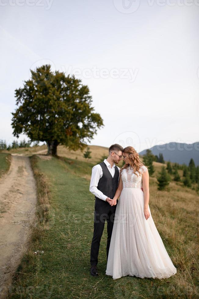 happy stylish bride and groom running and having fun in mountains on summer sunny day photo
