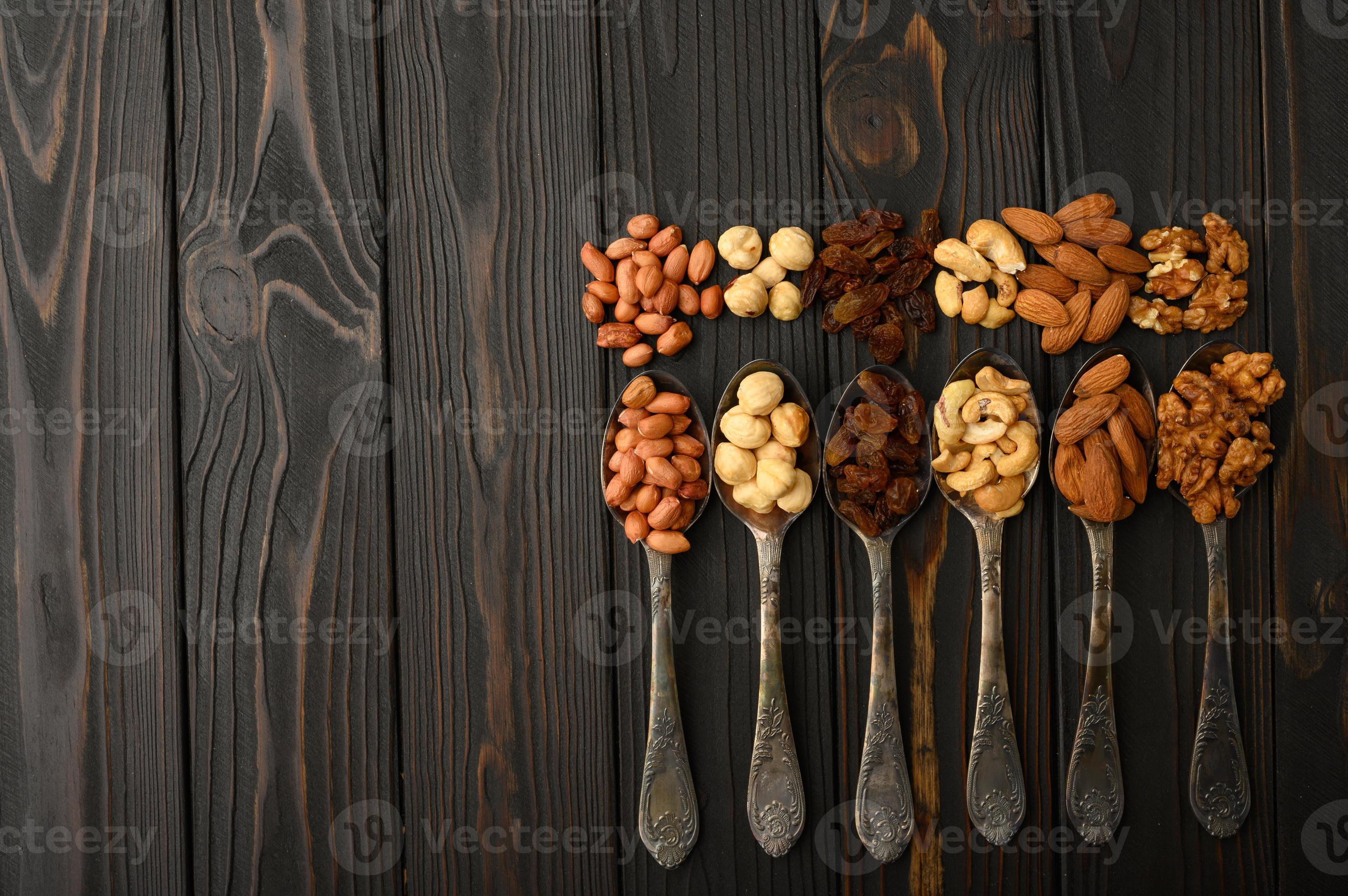Hazelnut, cashews, raisins, almonds, peanuts, walnuts in silver spoons