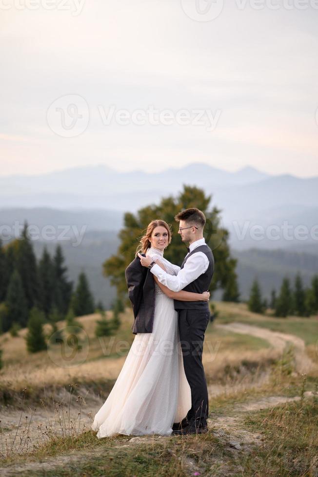happy stylish bride and groom running and having fun in mountains on summer sunny day photo
