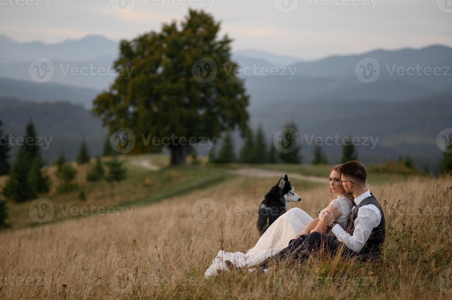 happy stylish bride and groom running and having fun in mountains on summer sunny day photo