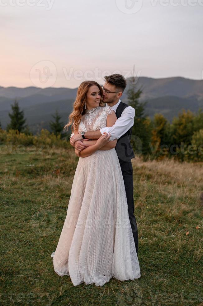 happy stylish bride and groom running and having fun in mountains on summer sunny day photo