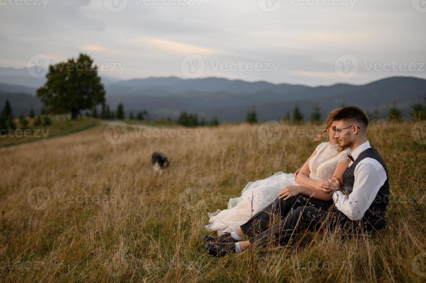 happy stylish bride and groom running and having fun in mountains on summer sunny day photo