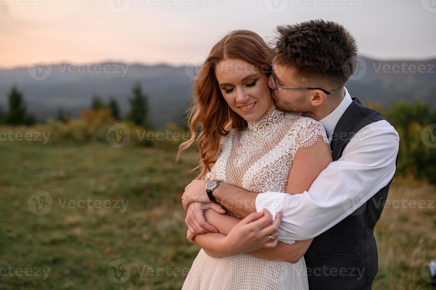 happy stylish bride and groom running and having fun in mountains on summer sunny day photo